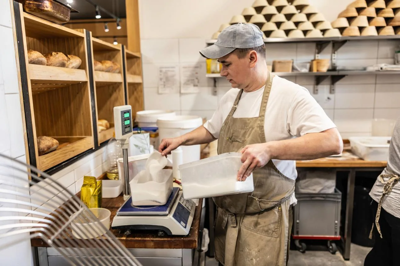 Baker cân và định lượng nguyên liệu bằng cân điện tử trong xưởng bánh