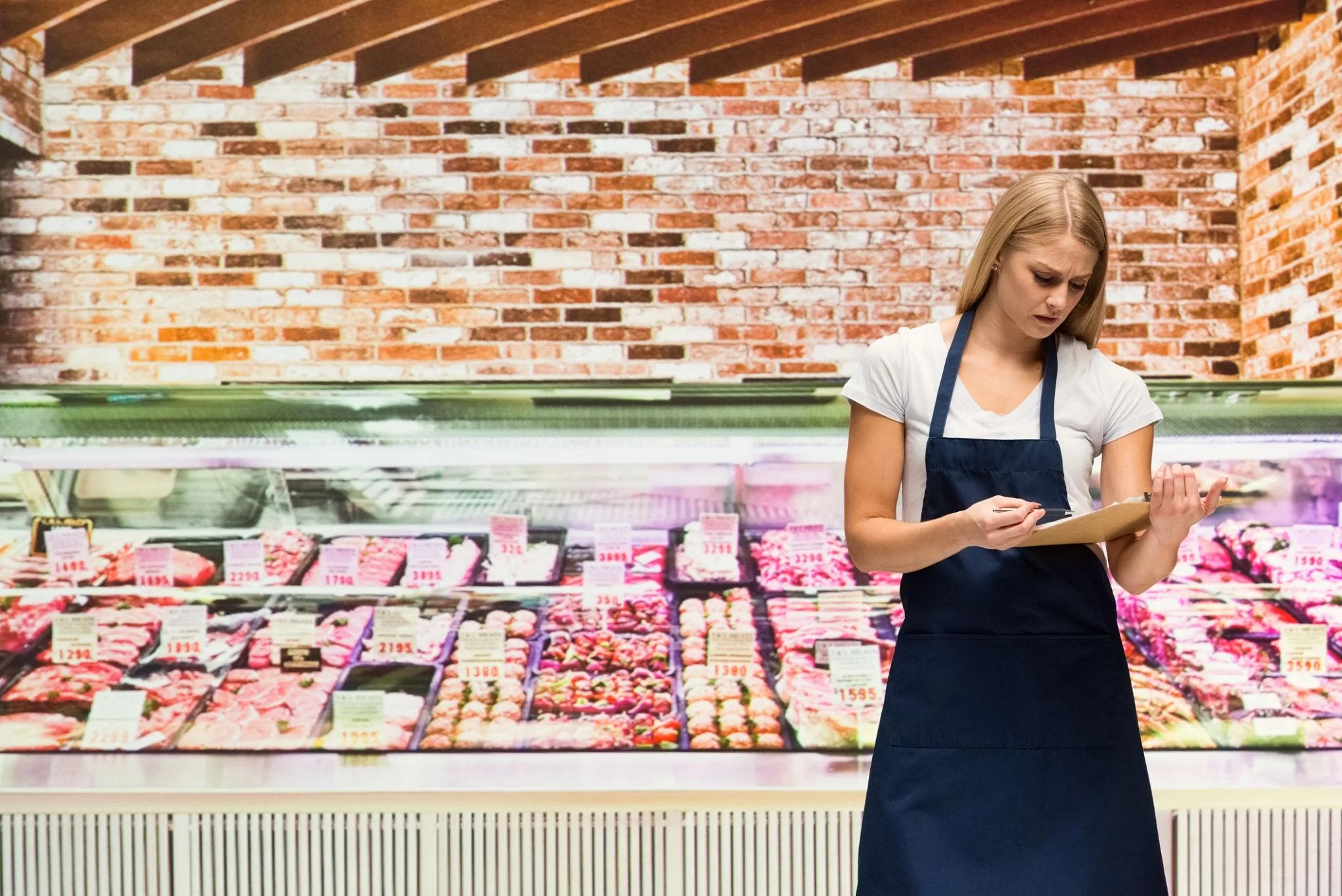 Nhân viên cửa hàng thịt Butcher kiểm tra hồ sơ và danh mục sản phẩm thịt