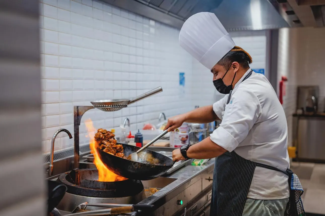 Đầu bếp Cook chế biến món ăn châu Á bằng chảo wok